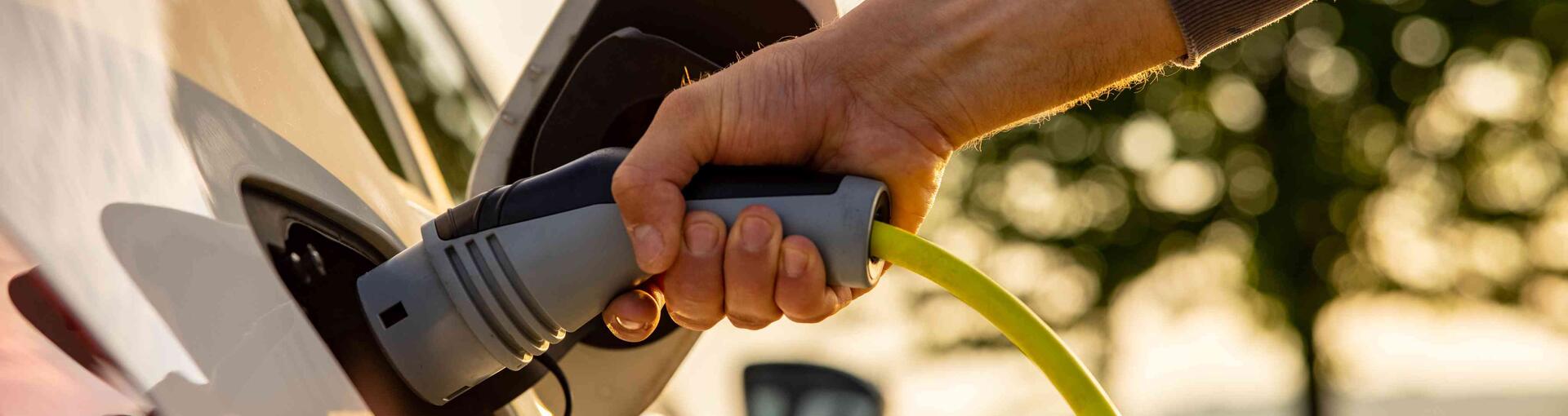 Hand plugging in car charger to electric vehicle 