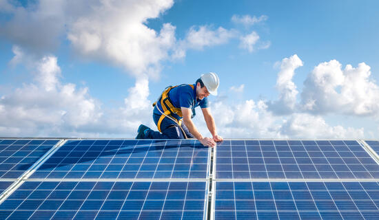 Professional worker installing solar panels on the roof of a house