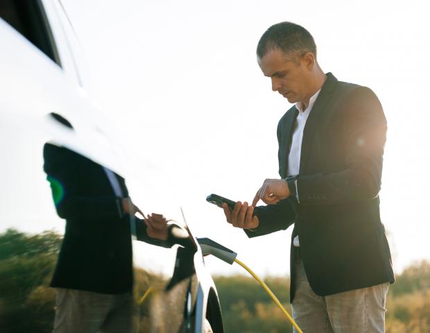 Male charging EV vehicle outdoors payment App
