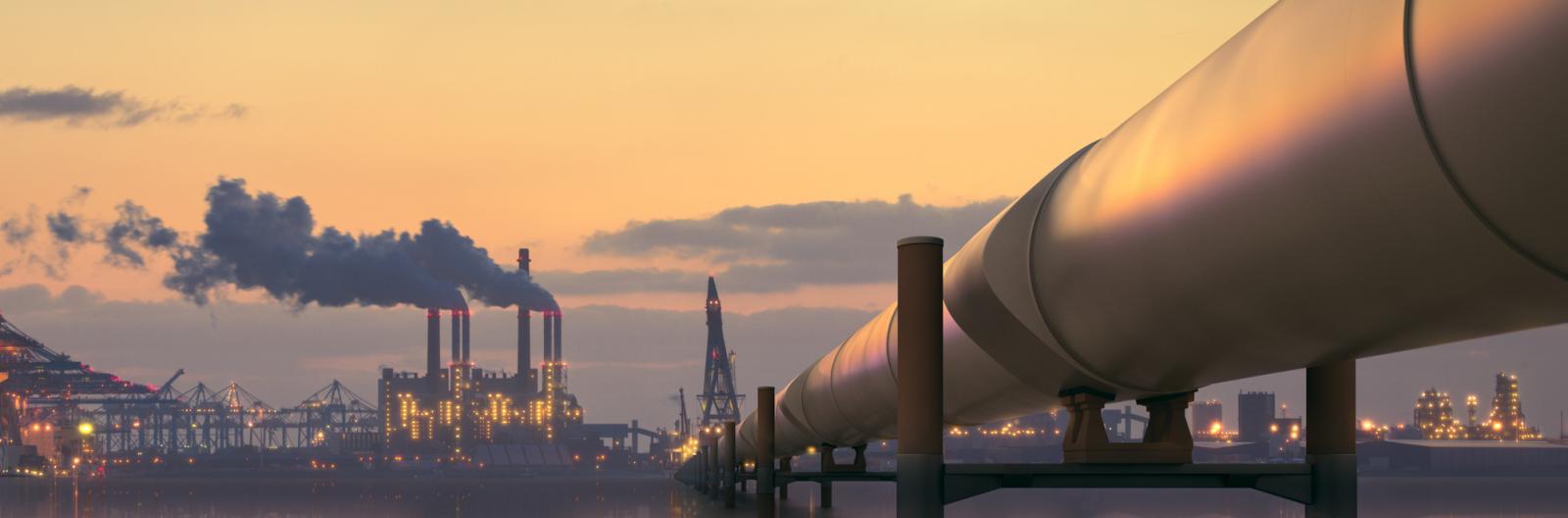 Oil pipeline in industrial district with factories at dusk